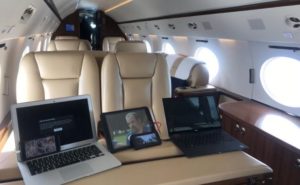 Three laptops, sitting on a table aboard a business jet