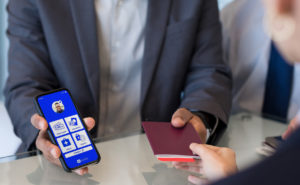 Copa Man handing a woman his passport wile also showing her IATA travel pass on his mobile device