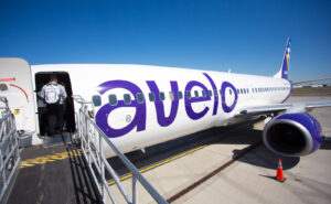 Avelo aircraft at the gate with an entry ramp extended for passenger to walk on.