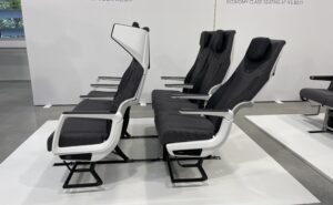 A showcase of the CL3810. Two seat triples - in shades of grey with white accents - are in view. The winged headrest for privacy is prominent.