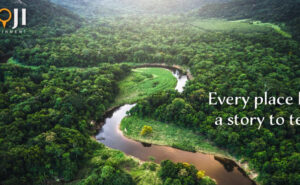 A stream running through green countryside, with the Goji logo and the message: "Every place has a story to tell."