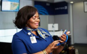 A United Airlines female crew member is standing at the gate holding an electronic device Many Crew Members will be protected with the CARES Act