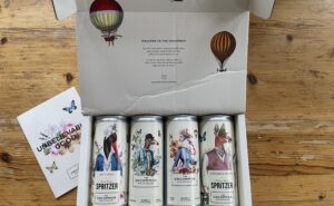 A box of 4 cans of sparkling wine is displayed on a table.