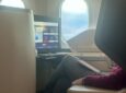 A passenger is watching IFE in a business class suite onboard an aircraft. He is also enjoying his own tablet. (IFC)