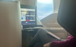 A passenger is watching IFE in a business class suite onboard an aircraft. He is also enjoying his own tablet. (IFC)